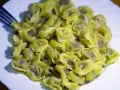 Talerz pełen ugotowanego tortellini z widelcem po lewej stronie.
